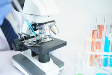 Asyalı bilim adamları laboratuvarda kimyasal bileşenleri ciddi şekilde inceliyorlar. Genç Biyoteknoloji Uzmanlığı Gelişmiş mikroskop ekipmanları kullanın.