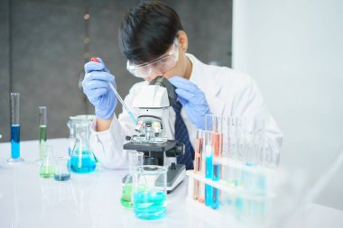 Asyalı bilim adamları laboratuvarda kimyasal bileşenleri ciddi şekilde inceliyorlar. Genç Biyoteknoloji Uzmanlığı Gelişmiş mikroskop ekipmanları kullanın.