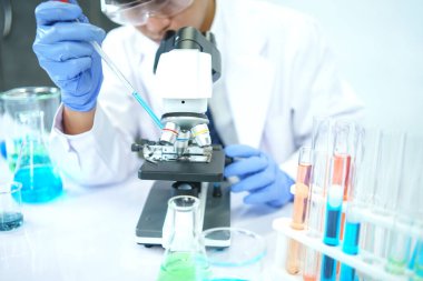 Asyalı bilim adamları laboratuvarda kimyasal bileşenleri ciddi şekilde inceliyorlar. Genç Biyoteknoloji Uzmanlığı Gelişmiş mikroskop ekipmanları kullanın.