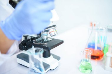 Asyalı bilim adamları laboratuvarda kimyasal bileşenleri ciddi şekilde inceliyorlar. Genç Biyoteknoloji Uzmanlığı Gelişmiş mikroskop ekipmanları kullanın.