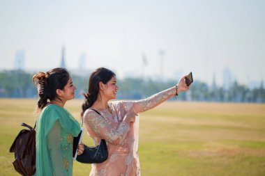 Wat Phra Kaew ya da Zümrüt Buda Tapınağı 'nda tatil yaparken akıllı telefonlarıyla selfie çeken Güney Asyalı turistler Bangkok Tayland' da turistik bir dönüm noktası.
