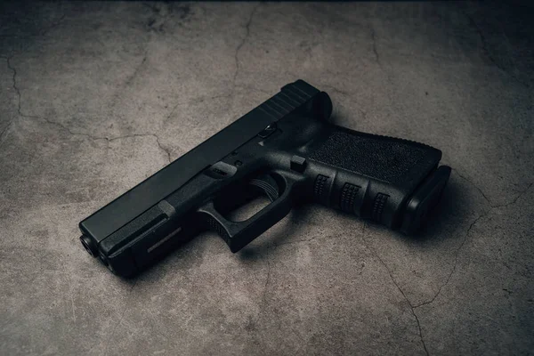 black 9mm pistol on an old concrete floor. top view.