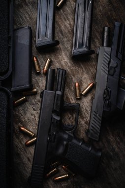 Two 9mm pistols hold slides on a wooden table.