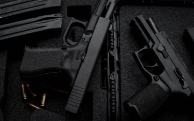 Two 9mm pistols hold slides on a wooden table.