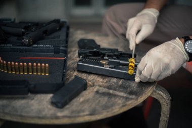 The gunsmith is sitting around cleaning the gun and disassembling and maintaining the pistol.