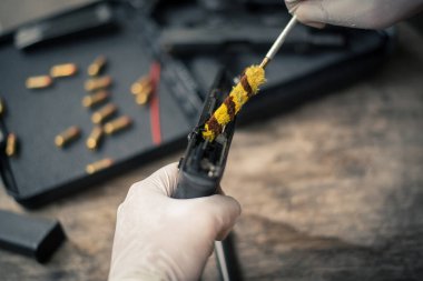 The gunsmith is sitting around cleaning the gun and disassembling and maintaining the pistol.