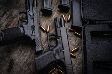 Two 9mm pistols hold slides on a wooden table.