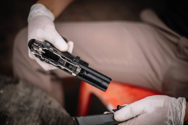 The gunsmith is sitting around cleaning the gun and disassembling and maintaining the pistol.