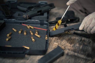 The gunsmith is sitting around cleaning the gun and disassembling and maintaining the pistol.