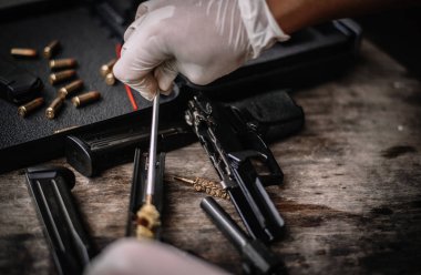 The gunsmith is sitting around cleaning the gun and disassembling and maintaining the pistol.