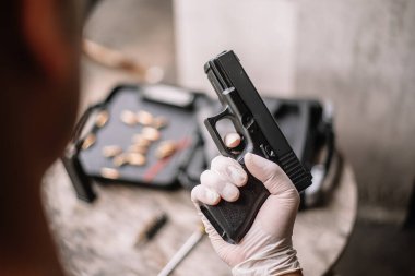 The gunsmith is sitting around cleaning the gun and disassembling and maintaining the pistol.
