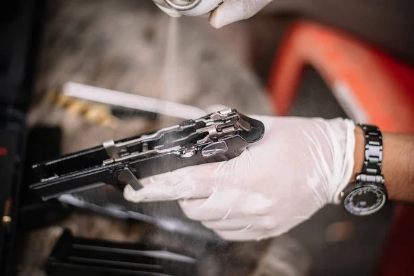 The gunsmith is sitting around cleaning the gun and disassembling and maintaining the pistol.