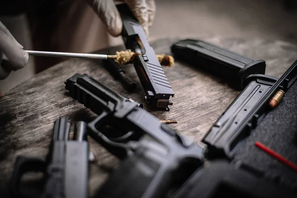 The gunsmith is sitting around cleaning the gun and disassembling and maintaining the pistol.