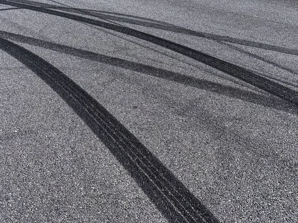 Asfaltlanmış sokakta siyah lastik izleri olan bir arka plan.