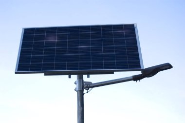 Mavi gökyüzüne karşı güneş paneli tarafından desteklenen lamba.