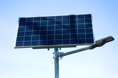 Mavi gökyüzüne karşı güneş paneli tarafından desteklenen lamba.