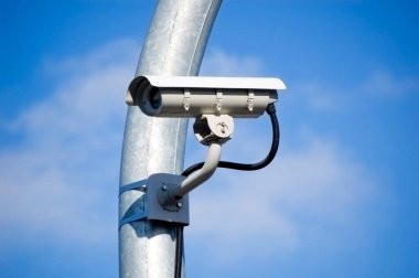 Mavi gökyüzüne karşı şehir izleme sistemi kamerası.