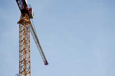 Büyük inşaat alanı vinci açık mavi gökyüzü olan bir bina tesisinde çalışıyor..