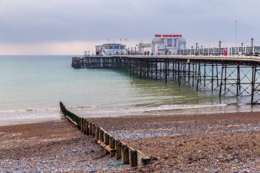 Worthing, West Sussex, England, UK - October 25, 2016: The pier seen from Worthing beach with grey clouds over the sea clipart