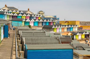 Walton-on-the-Naze, Essex, İngiltere - 29 Mayıs 2017: Southcliff Gezinti Güvertesinde sahil kulübeleri, bazı insanlar ve arka planda Walton İskelesi