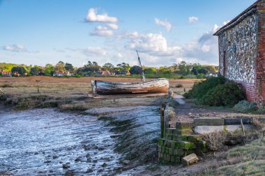 Thornham, Norfolk, İngiltere, İngiltere - 24 Nisan 2019 Thornham Old Harbour 'da yanında ahşap yelkenli teknesi olan eski bir taş ahır