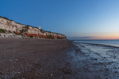 Hunstanton, Norfolk, İngiltere, İngiltere - 25 Nisan 2019: Deniz feneri ve uçurumlar üzerinde akşam ışığı ve bulutları