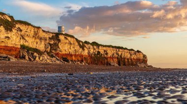 Hunstanton, Norfolk, İngiltere, İngiltere - 25 Nisan 2019: Deniz feneri ve uçurumlar üzerinde akşam ışığı ve bulutları