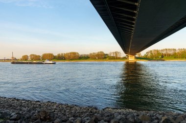 Duisburg, Kuzey Ren-Vestfalya, Almanya - 11 Nisan 2020: Neuenkamp 'taki otoyol köprüsünün altındaki Ren Nehri' nde bir kargo gemisi