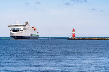 Rostock, Mecklenburg-Batı Pomerania, Almanya - 14 Haziran 2020: Gedser 'den Rostock' a giden bir Scandline feribotu, Warnemuende 'deki doğu rıhtımındaki deniz fenerini geçiyor.