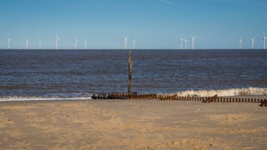 Kuzey kıyısı Caister-on-Sea, Norfolk, İngiltere - bir dalga kırıcı ve arka planda rüzgar türbinleri ile