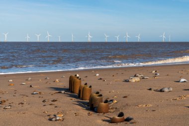 Kuzey kıyısı Caister-on-Sea, Norfolk, İngiltere - Sahilde bir dalga kırıcı ve arka planda rüzgar türbinleri ile