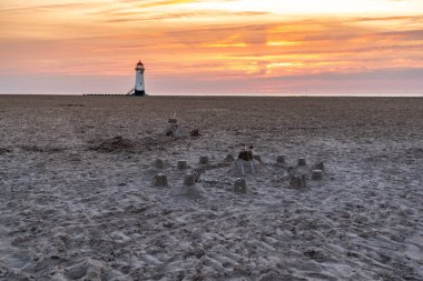 Sahilde kumdan kaleler, akşam bulutları ve arka planda Ayr Deniz Feneri Noktası ile, Talacre, Flintshire, Galler, İngiltere yakınlarında.