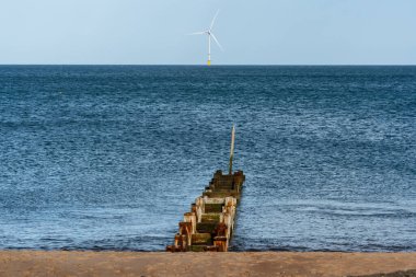 Northumberland, İngiltere 'de Seaton Sluice yakınlarında Kuzey Denizi kıyısında arka planda bir rüzgar türbini var.