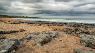 Northumberland, İngiltere 'deki Berwick-upon-Tweed yakınlarındaki Cocklawburn Sahili' nde kara bulutlar ve büyük taşlar görülüyor.