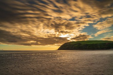 Cumbria, İngiltere 'deki Whitehaven yakınlarındaki St Bees Heritage Sahili üzerinde gün batımı ve kara bulutlar.