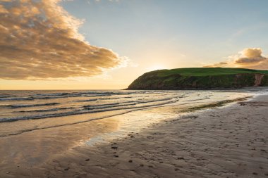 Cumbria, İngiltere 'deki Whitehaven yakınlarındaki St Bees Heritage Sahili üzerinde gün batımı ve kara bulutlar.