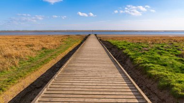 Lytham, Lancashire, İngiltere 'de görülen Ribble Nehri kıyısına giden tahta bir patika.