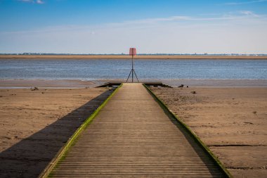 Lytham, Lancashire, İngiltere 'de görülen Ribble Nehri kıyısına giden tahta bir patika.