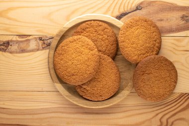 Yuvarlak ahşap bir tepside, yakın planda, ahşap bir masada birkaç lezzetli yuvarlak Amerikan kurabiyesi..