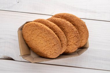 Kağıt bir kutuda, ahşap bir masanın üstünde, üst manzaralı birkaç lezzetli yuvarlak Amerikan kurabiyesi..