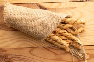 Grissini ekmek çubukları susam tohumlu jüt peçeteli, yakın plan, ahşap bir masa, üst görüş.