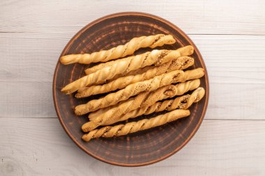 Kil tabakta susamlı Grissini ekmek çubukları, yakın plan, ahşap masa, üst görüş.