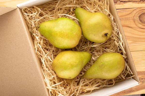 Tahta bir masada, makroda, üst manzarada, talaş kutusunda dört tatlı armut..