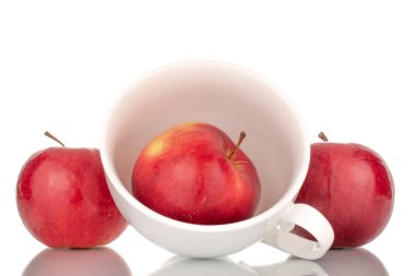 Üç sulu, olgun, beyaz seramik bardaklı kırmızı elma, makro, beyaz arka planda izole edilmiş..