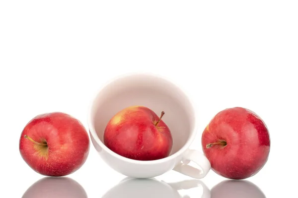 Üç sulu, olgun, beyaz seramik bardaklı kırmızı elma, makro, beyaz arka planda izole edilmiş..