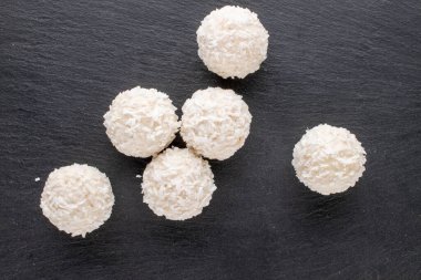 Tahtada hindistan cevizi taneleri olan yuvarlak beyaz şekerler, yakın plan, üst görünüm..