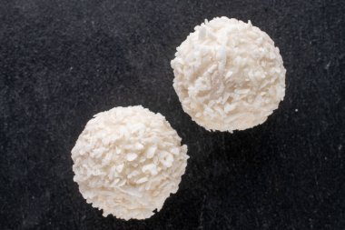 Tahtada hindistan cevizi taneleri olan iki yuvarlak beyaz şeker, yakın plan, üst manzara..