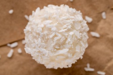 Kahverengi kağıt üzerinde hindistan cevizi taneleri olan yuvarlak beyaz bir şeker, yakın plan, üst manzara..