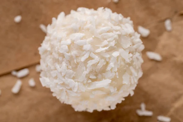 Kahverengi kağıt üzerinde hindistan cevizi taneleri olan yuvarlak beyaz bir şeker, yakın plan, üst manzara..