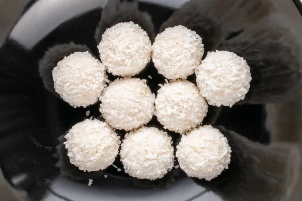 Kilka Pysznych Słodyczy Płatkami Kokosowymi Czarnej Ceramicznej Płycie Zbliżenie Widok — Zdjęcie stockowe
